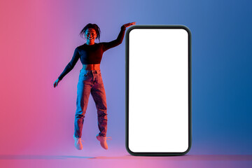 Poster - Overjoyed black lady jumping near big smartphone with blank screen, colorful neon light, collage, mockup