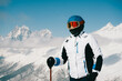 Portrait skier at ski resort standing on sunny day against backdrop of beautiful mountain peaks in the clouds
