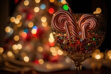 Bokeh Of A Lighted Christmas Tree And Garlands In A Crystal Wine Glass Filled With Red Striped Heart Shaped Lollipops. The Winter Break Was A Lot Of Fun. Feeling Of Celebration That Comes With The New