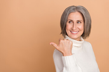 Poster - Photo portrait of promoter middle aged senior woman point finger look empty space recommend new stomatology isolated on beige color background