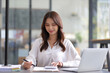 © Wasan - Young beautiful asian businesswoman in office working with laptop and financial documents on desk.