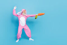 Full Length Photo Of Charming Cool Pensioner Guy Dressed Bunny Kigurumi Fighting Carrot Sward Empty Space Isolated Blue Color Background
