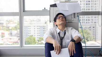 Overload office worker. Alone stressed and sad  asian office worker is sitting beside error copy machine at the office.