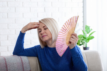 mature woman experiencing hot flush from menopause. this photo captures the discomfort of hot flashe