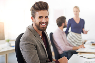 Leinwandbilder - Hes one confident exec. A businessman sitting at his desk with his coworkers in the background.