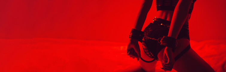 woman with a sexy ass with handcuffed hands sits erotically on bed in bedroom. bdsm concept of sex w