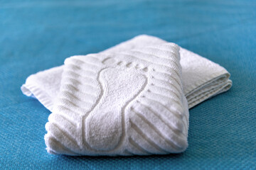 A stack Clean white bath towels lying on bed in hotel suite, close-up and selective focus