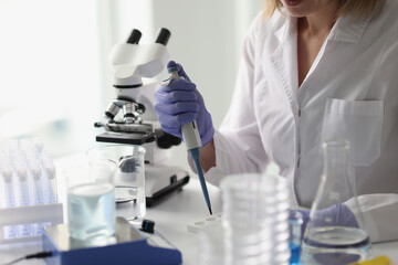 Professional woman scientist with pipette in her hand is working in scientific laboratory.