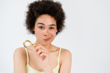 Wall Mural - Young african american woman grimacing and holding candy cane isolated on grey.