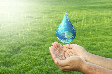 World water day concept: hands holding earth in drop shape  on blur nature background. Elements of this image furnished by NASA