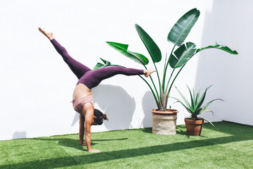 Wall Mural - Caucasian strong yogi doing hatha pose for training body balance during morning physical retreat at terrace, motivated female exercising have active workout for slimming and feeling vitality