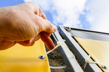 fastening process of the outdoor ad banner to the metal frame with the help of plastic cable ties