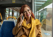 © PintoArt - beautiful mature woman traveler talking on cell phone while taking the bus to work