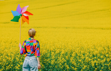 Sticker - Beautiful female in 90s stylish shirt with pinwheel in rapeseed field