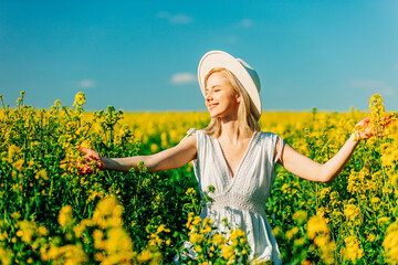 Wall Mural - Beautiful woman in dress in rapeseed field