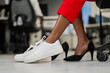 © Михаил Решетников - African woman changing from high heels to sneakers in the office. Tired legs.