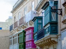 Fragment Of The Building's Facade With Traditional Wooden Ornate Balconies Painted In Valletta, Malta. High Quality Photo