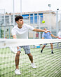 © JackF - Portrait of sporty young guy playing padel on open court on summer day, ready to hit ball. Sport and active lifestyle concept..