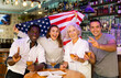 © JackF - Excited diverse soccer fans with American flag rejoicing winning game with glasses of beer in the pub