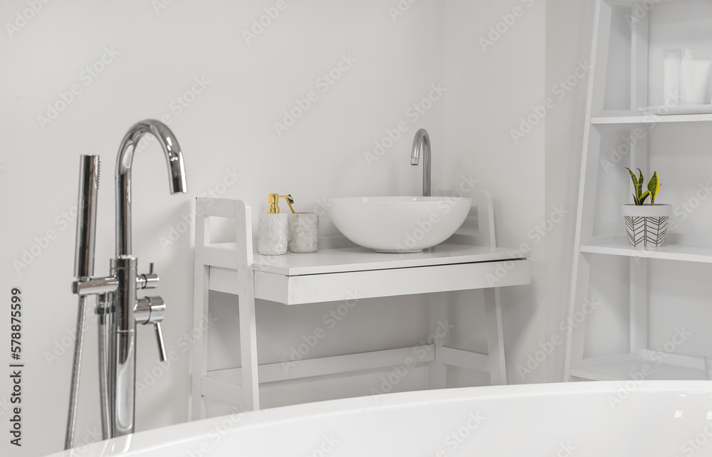 Sink with soap bottle and toothbrush on table in light bathroom