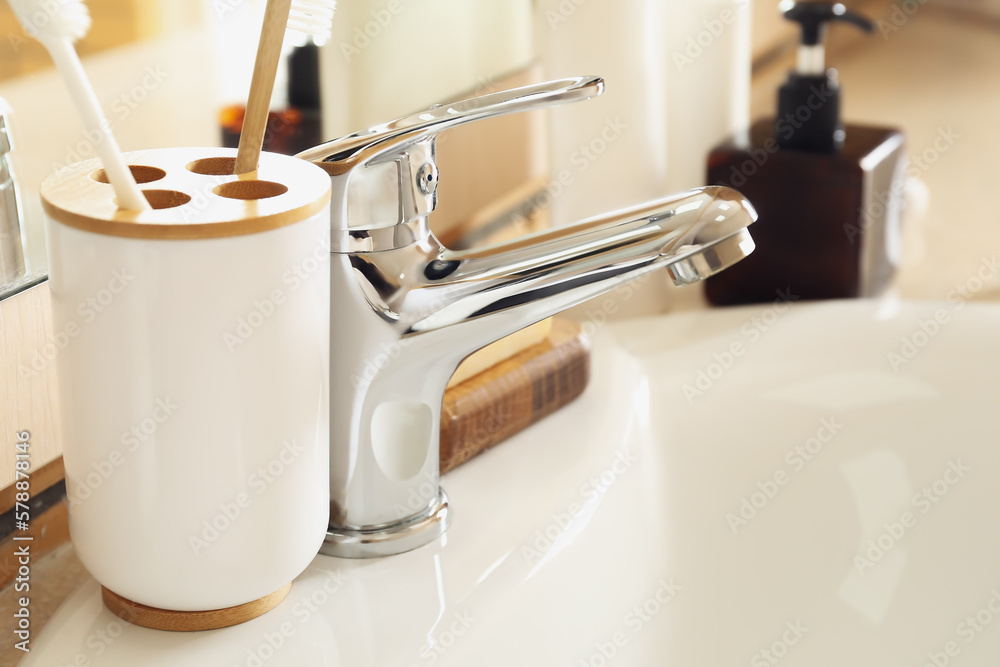 Holder with toothbrushes on white sink, closeup