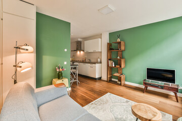 Wall Mural - a living room with green walls and wood flooring, including a grey couch in the center of the room