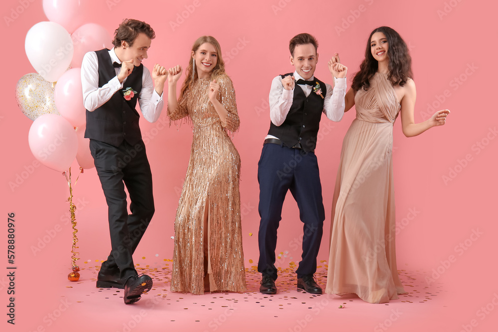 Beautiful couples dressed for prom dancing on pink background