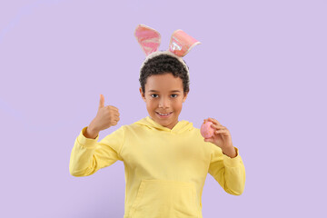 Sticker - African-American little boy in bunny ears with Easter egg showing thumb-up on lilac background