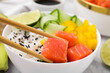 © New Africa - Delicious poke bowl with salmon, lime and vegetables on table, closeup