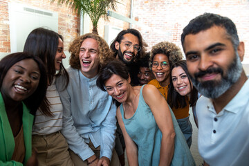 Happy multiracial group of coworkers take selfie together in the office.