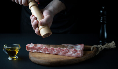 Wall Mural - the chef sprinkles the meat with spices and salt, the concept of the restaurant menu