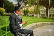 A Latin man basks in the sun while catching up with a friend on his phone in the plaza