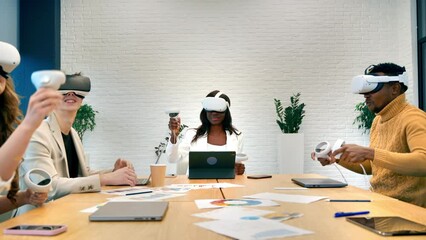 Wall Mural - Business conference in VR in an office. Multiracial group of people using VR glasses and controllers, papers and gadgets on the table