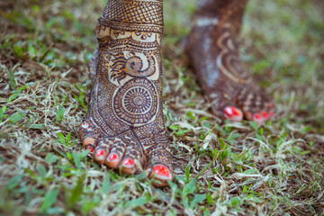 Mehendi on feet of the bride walking in grass