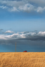 Red Car Against A Background Of Blue Sky And Clouds
