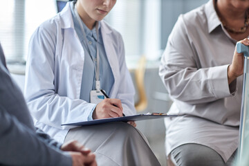 Wall Mural - Close up of female therapist writing on clipboard while overseeing mental health support group for seniors, copy space