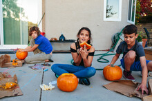 Girl Shows Camera The Top Of Her Pumpkin During Carving With Siblings