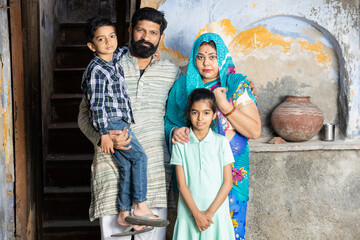 Wall Mural - Young indian rural family standing looking at camera, Happy farmer family, Parents with children.