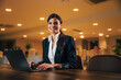 © bnenin - Pretty woman typing on a laptop, sitting in the meeting room, smiling for the camera.