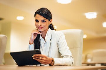 Portrait of a pretty businesswoman holding a digital tablet, sitting at the workplace.