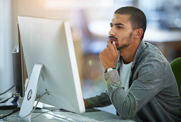 Poster - This is going to take some thought...a young designer deep in thought while working on a computer in a modern office.