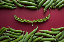 Green Pea Pods Laid Out On A Red Background. Top View. Food Concept. 