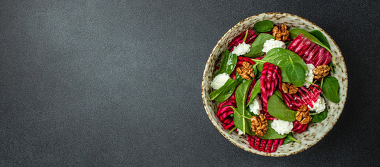 Wall Mural - Healthy Beet Salad with baby spinach, nuts and cheese on a dark background. Long banner format. top view