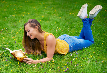 Sticker - Reading is like dreaming with your eyes open. a carefree young woman relaxing in a field of grass with a book.