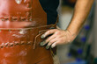 © primipil - Man sculptor dressed leather apron with clay in hands. Statue craft creation workshop.