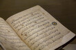 Ancient open book manuscript (verses of Koran Book, Holy Islamic Text). XIII-th century arabic book pages. Selected focus, shallow depth. Copy space, grunge background