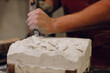 © primipil - Man sculptor creates sculpt bust gypsum human woman sculpture with hammer. Statue craft creation workshop.