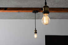 Loft Style Elements In The Interior. Vintage Incandescent Light Bulbs Are Spotted On Wooden Beams On A Bare Concrete Ceiling.