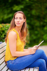 Poster - I wonder what the parks wifi password is.a young woman using a digital tablet on a park bench.