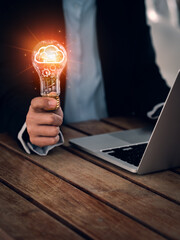 Poster - Business solution, learning and creative idea management concepts. Glowing brain symbol and cogs, management icon system inside light bulb, hold by business people who work with computer, vertical.